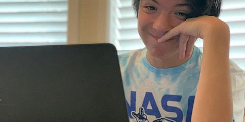 student smiling while working at laptop