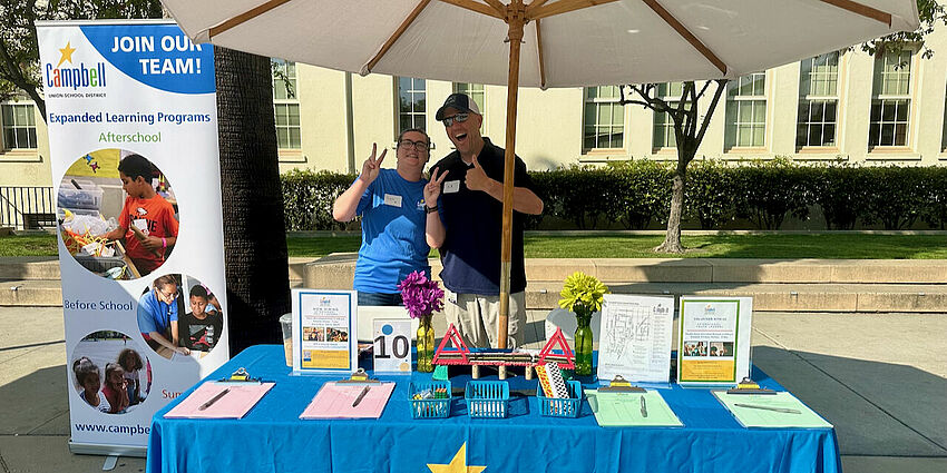 man and woman employees at an exhibitor table at a hiring event