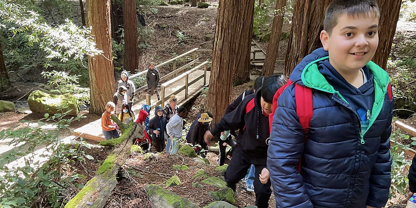 smiling boy leads students on a nature trail