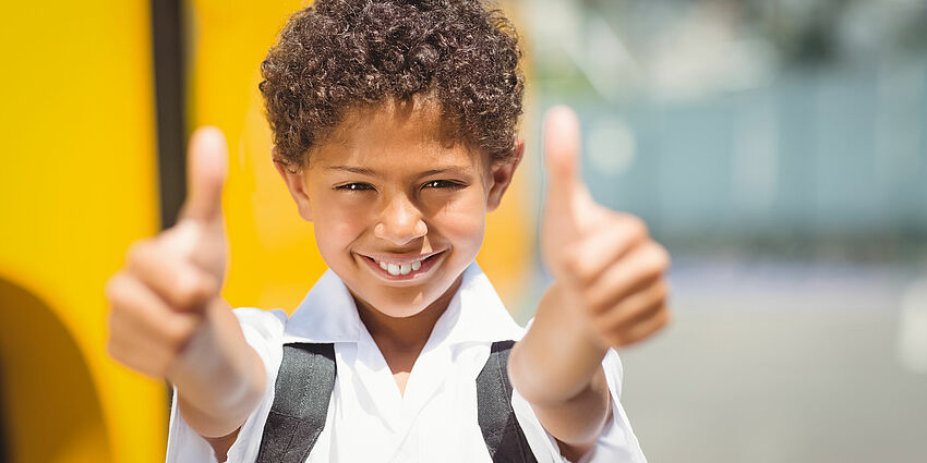 elementary school boy smiles and gives 2 thumbs up