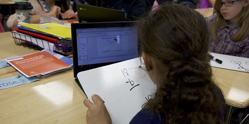 child writing a math problem in class