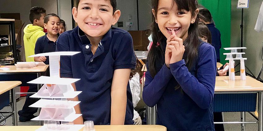 two students with a stack of cards made of paper