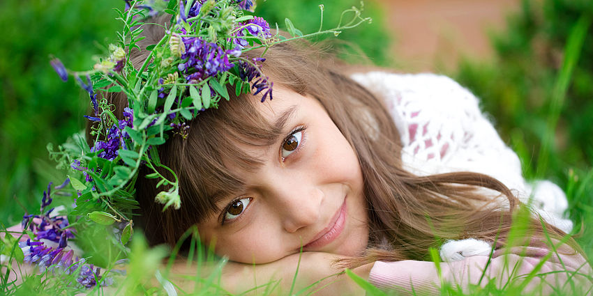 smiling young girl resting on grass and flowers
