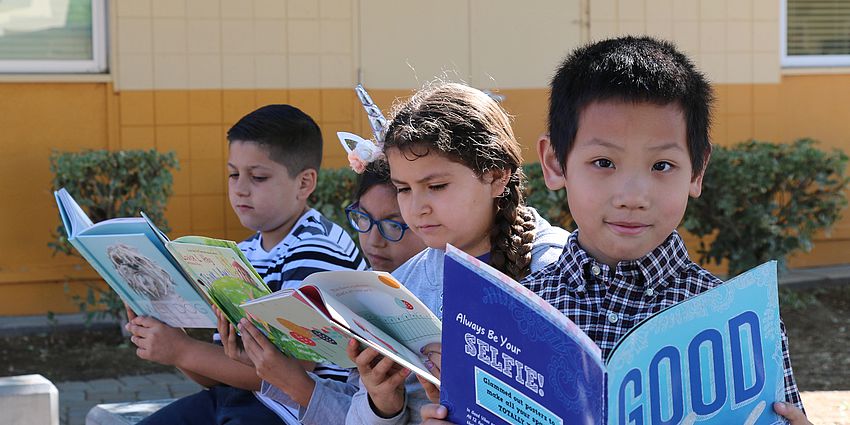 four children reading outside