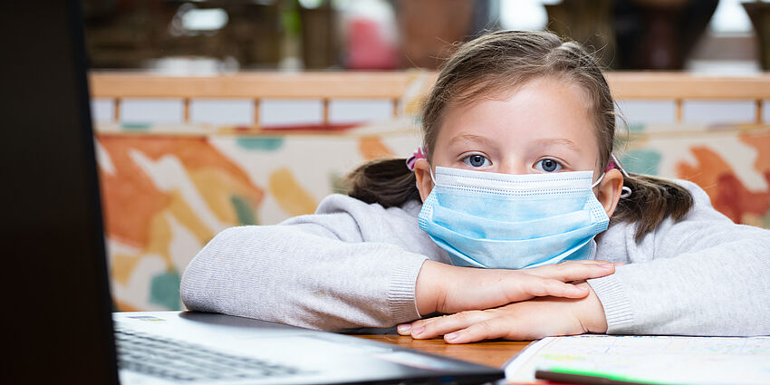 girl beside computer, wearing mask 