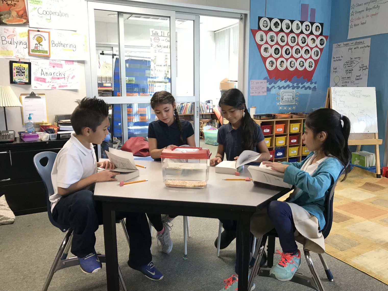 four kids in uniforms reading together at a table