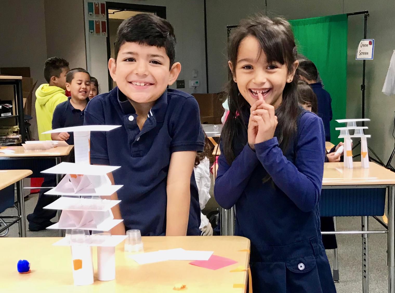 two students with a stack of cards made of paper