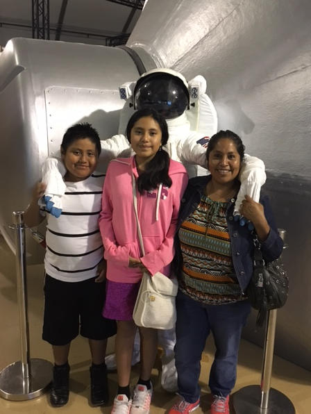 mom and kids pose with astronaut's space suit at NASA